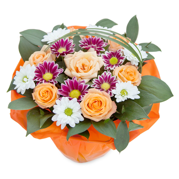 From an artful, overhead perspective against a gleaming white background, this bouquet bursts with the inviting colours of Tooting's floral heritage. Warm peach and lively orange roses, their petals gently unfurling in classic whorls, take centre stage, forming a radiant focus in the arrangement. Interspersed are soft white, daisy-like chrysanthemums with pale green hearts, alongside striking magenta-purple blooms creating a dramatic contrast of tone. Generous swathes of dark, glossy greenery-possibly ruscus-loom beneath, peeking up to provide a lush, verdant cushion and adding fullness to the presentational silhouette. Atop the composition, thin, curving bear grass loops elegantly, nodding to modern design trends. The base is expertly wrapped in vivid, crinkled orange paper, reflecting the zesty character of Tooting's Graveney area and setting a celebratory mood. Thoughtfully crafted by local hands, this bouquet radiates the joy of togetherness, making it the perfect accompaniment for parties, expressions of gratitude, or brightening quiet corners of family homes throughout Tooting.