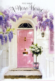 This scene shows a pastel-toned front door that could easily be found on a calm residential street off Tooting High Road, made especially welcoming with flowers and trailing wisteria. The door is painted a tender pink, its surfaces smooth and luminous, drawing the eye immediately. Around it, the frontage is softly whitewashed, catching the light in a way that makes everything feel serene and bright. From somewhere above, abundant wisteria falls in flowing cascades of lavender and soft violet, the blossoms hanging in long clusters that create a dreamy canopy over the entrance. The blooms brush past a delicately painted shutter and form gentle shadows along the wall, hinting at the breeze that might be carrying their perfume down towards Tooting Bec. On the doorstep, a sturdy grey bucket sits firmly in place, filled to the brim with creamy white roses. The roses are open and full, with velvety petals that look almost touchable, nestled among sprigs of fresh, light green foliage that add texture and natural movement. A pretty pink ribbon is tied around the bucket, the satin bow reflecting the same warm hue as the door and binding the scene together visually. Soft, filtered light grazes the steps, giving everything a golden, late-afternoon hush. The mood is tender and hopeful, perfectly capturing the feel of a housewarming moment: perhaps a friend has arranged for Flowers Tooting to leave this bouquet at the door, so the new homeowners are greeted not just by keys and boxes, but by fragrance, colour, and a sincere, floral welcome home.